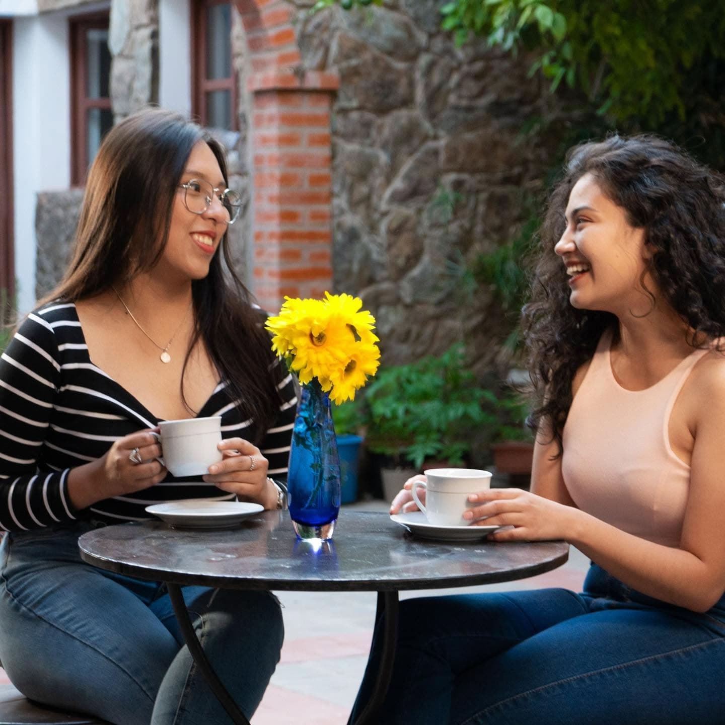 Café en el patio: Un rincón exterior para conversar con calma entre plantas y detalles de piedra.